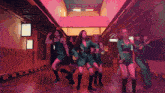 a group of young women are dancing in a hallway with a sign that says ' a ' on it