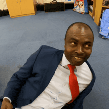 a man in a suit and tie is sitting on the floor and smiling