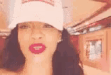 a close up of a woman wearing a hat and red lipstick .
