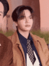 a man in a suit and tie is sitting next to another man .