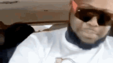 a man wearing sunglasses is sitting in a car and making a funny face .