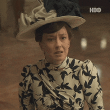 a woman wearing a hat and a dress with a hbo logo