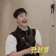 a man wearing a black vest and a white shirt is laughing in a room