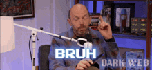 a man is sitting in front of a microphone with the words bruh dark web written on the screen .