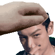 a man is covering his nose with his hand while a hand is holding his head .
