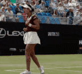 a woman is holding a tennis racquet on a tennis court in front of a lexus advertisement