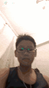 a young man wearing glasses and a black tank top takes a selfie