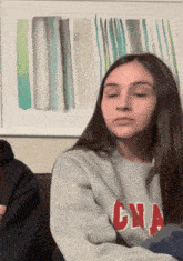 a girl wearing a grey sweater with cna written on it