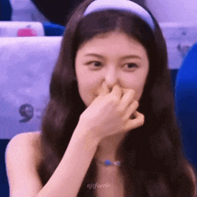 a woman is covering her nose with her hand while sitting in a plane .