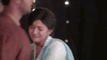 a man and a woman are standing next to each other and a woman is crying .