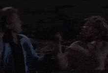 a woman in a blue jacket is talking to a man in a black shirt
