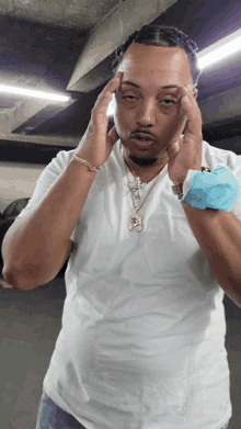 a man wearing a white shirt and a necklace with the letter s on it