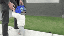 a person is holding a child 's hand with a blue gorilla face on it