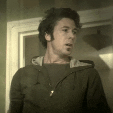 a man wearing a hoodie stands in front of a doorway
