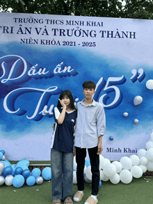 a boy and a girl are posing in front of a banner that says truong thcs minh khai