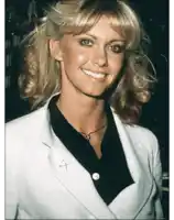 a woman wearing a white jacket and a black shirt has a pin with an arrow on it