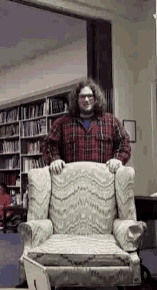 a man in a plaid shirt sits in a chair