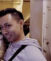 a man is smiling in front of a wall with the words delusionalforharmony on it