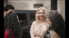 a group of people are standing around talking to each other on a street .