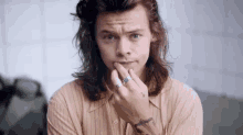 harry styles is wearing a striped shirt and a tattoo on his arm .