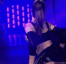 a woman in a black outfit is dancing on a stage with a microphone .