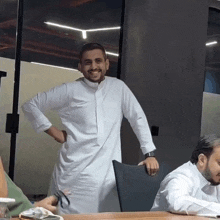 a man in a white robe is standing with his hands on his hips and smiling