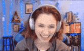 a woman wearing headphones is smiling in front of a blue wall