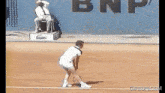 a man playing tennis on a court with a bnp sign in the background