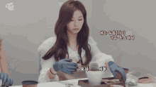 a woman sitting at a table with a potted plant and a twice logo