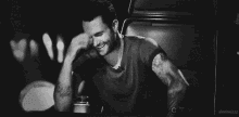 a black and white photo of a man laughing and covering his face
