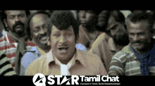 a group of men are gathered in a room with a star tamil chat logo on the bottom