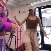 a woman in a brown tank top is dancing in a room with a man in a purple jacket .