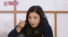 a woman is eating food with a spoon while sitting on the floor .