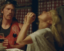 a man and a woman sit at a table with a woman covering her face
