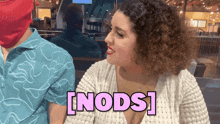 a woman in a white top with the word [ nods ] on her chest