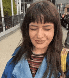 a woman wearing a denim jacket and striped shirt is smiling