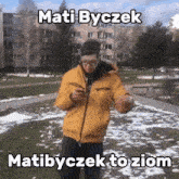 a man in a yellow jacket is holding a football and looking at his phone