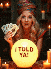 a woman holding tarot cards in front of a glowing ball that says " i told ya "