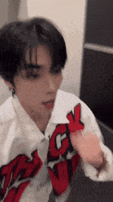 a blurry picture of a young man wearing a white shirt with red and black letters that says ck on it