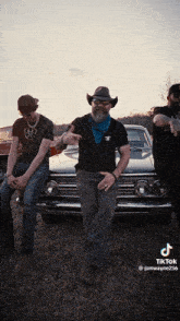 a man in a cowboy hat is standing next to two other men