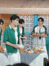 a man in a green shirt is standing in front of a table with plates of food on it