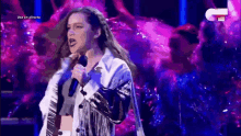 a woman with long hair is singing into a microphone on a stage .