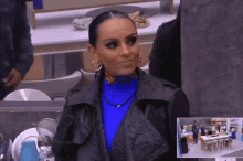 a woman in a blue turtleneck and black leather jacket