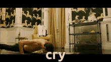 a shirtless man is doing push ups in a living room with the word cry behind him