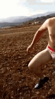 a man in underwear is running through a dirt field .