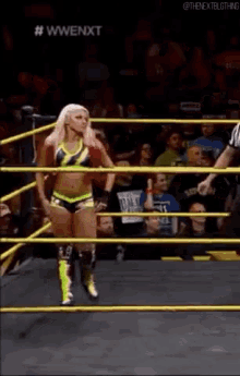 a female wrestler is standing in a wrestling ring with a referee behind her ..