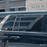 a black car is parked in front of a building that has the word naas on it