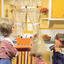 two dolls are playing in a kitchen with a toaster