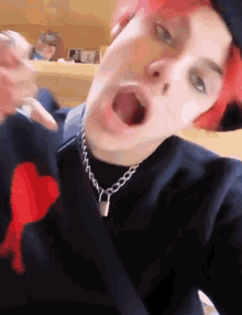 a person with red hair is wearing a black sweater with a heart on it