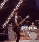 a man in a suit is playing a guitar and singing into a microphone